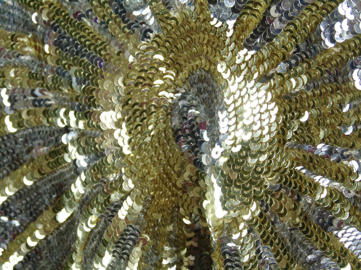 Gold, silver, and dark sequin capelet with radial starburst pattern and tie neckline