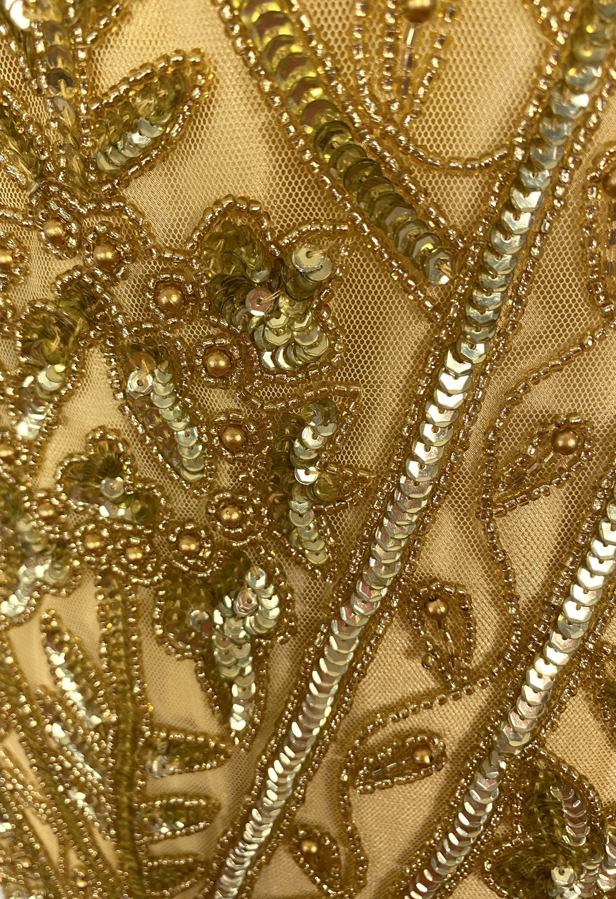 Close-up of gold bead and sequin embroidery with decorative swirl pattern