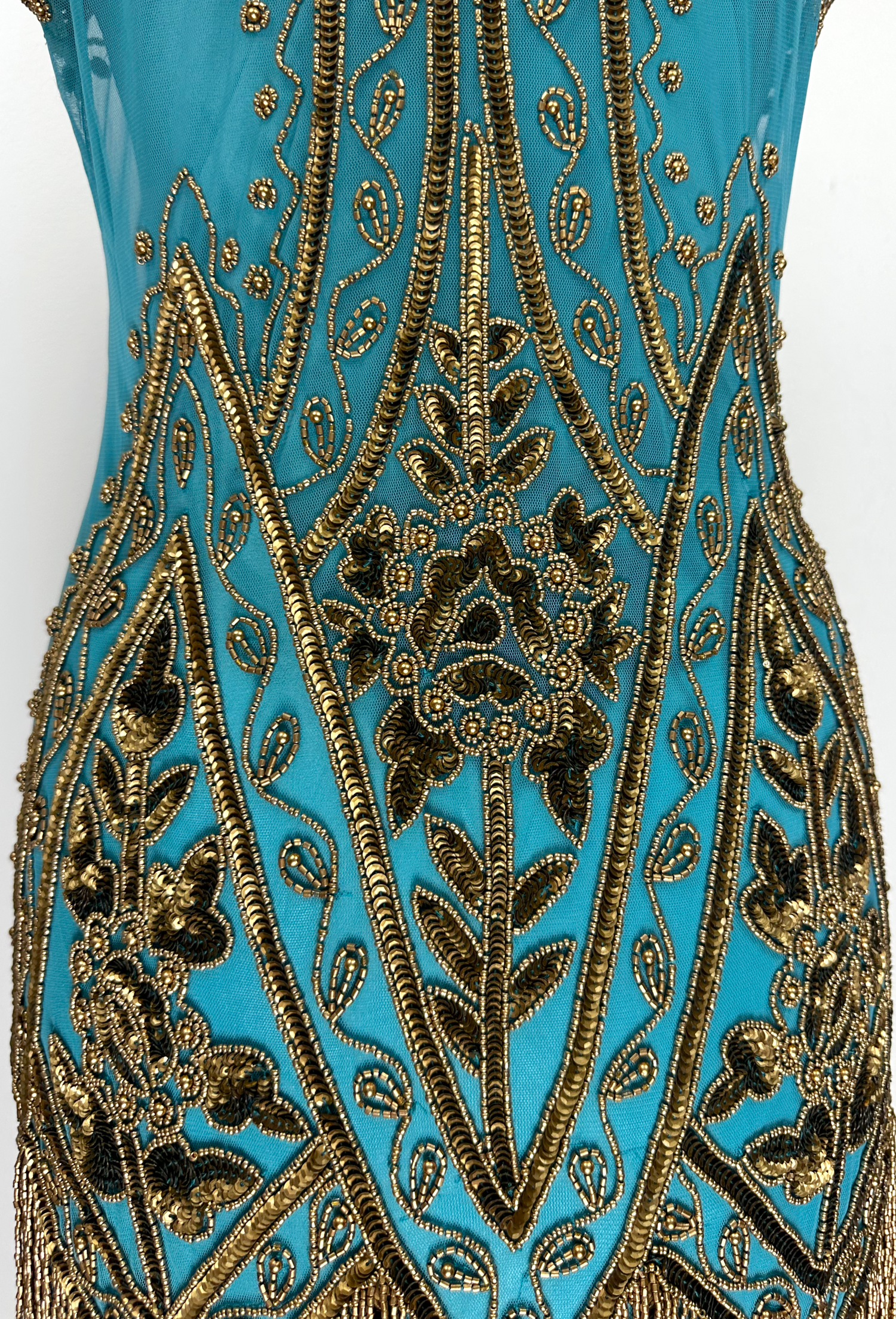 Close-up teal gown with ornate gold bead embroidery and scalloped trim