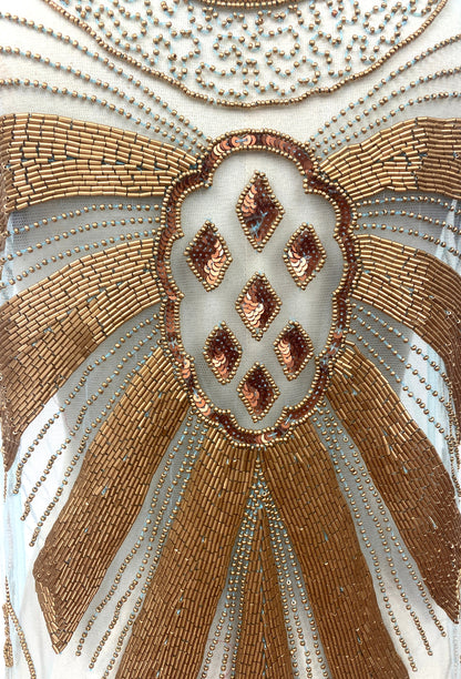 Close-up of gold and turquoise beaded emblem with diamond-shaped accents on overlay