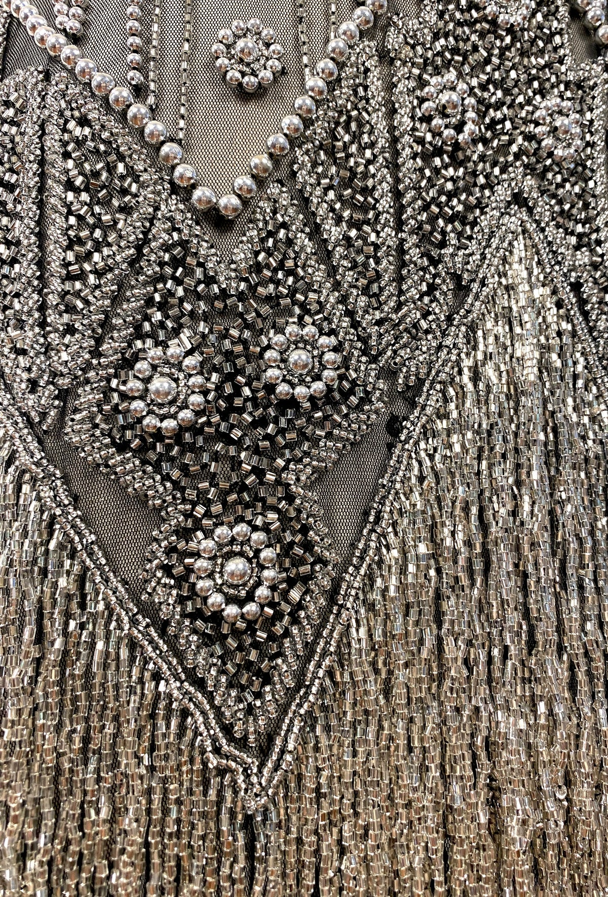 Beaded V-neck embellishment with clustered rhinestones and dangling fringe texture.