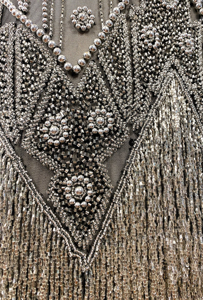 Beaded V-neck embellishment with clustered rhinestones and dangling fringe texture.