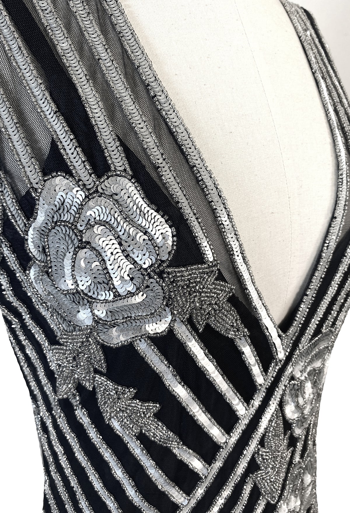 Close-up of silver beadwork and striped sequin panels on dark V-neck gown